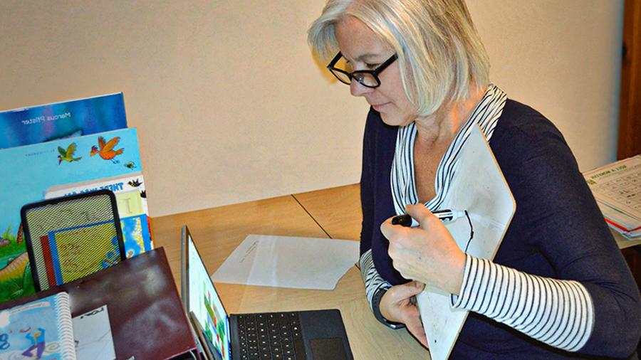 A therapist looks at a laptop screen as she carries out a telehealth appointment