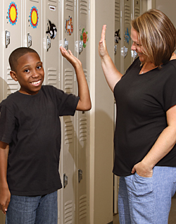 Mikey gives his teacher, Gabriela Bandi, a high-five in front of his locker at Kennedy Krieger High School.