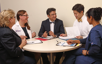 Staff members of the Pain Rehabilitation Program sit at a circular table, discussing the day’s schedule.