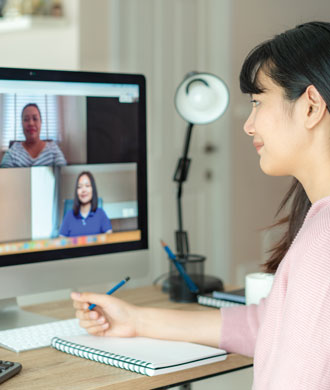 Back view of a woman talking to her colleagues in a video conference.