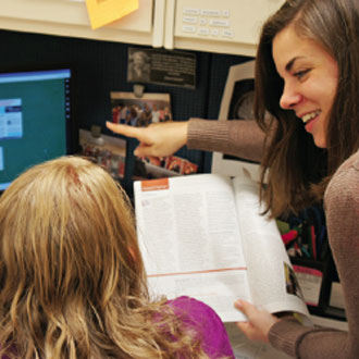 A teacher and her student look at a computer screen. 