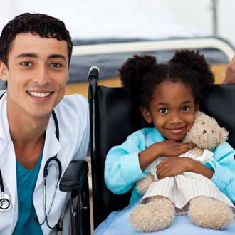 A doctor poses for a photo with a young girl in a wheelchair