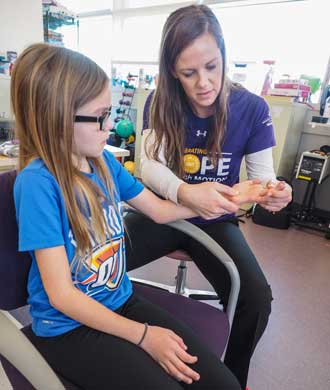 An occupational therapist performs therapy with her patient, a young girl.