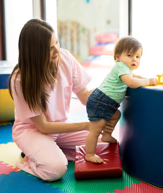 A physical therapist works with her patient, a toddler. 