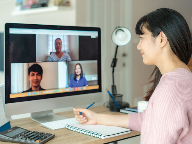 Back view of a woman talking to her colleagues in a video conference.