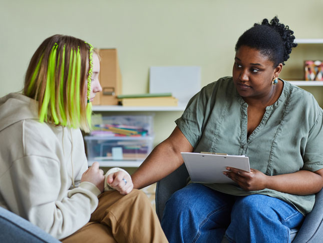 A social worker supports a sad teenage girl during a difficult situation.