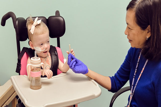 A young child in the feeding program receives a snack from a therapist.