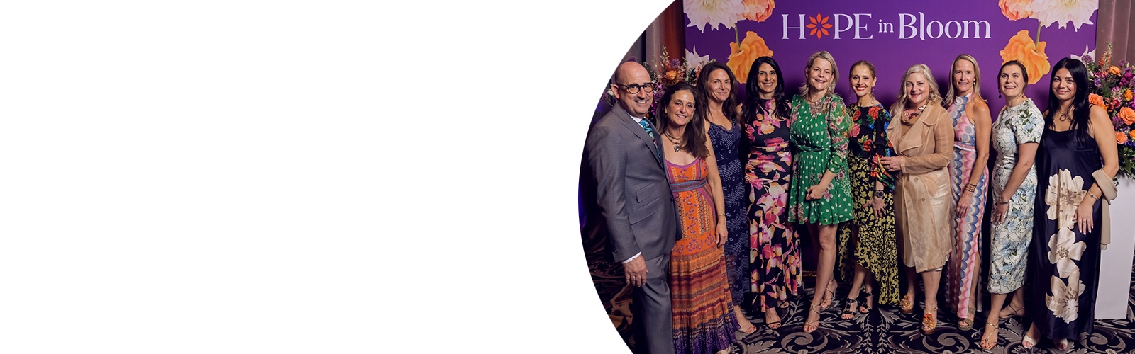 A group of Hope in Bloom attendees while standing in front of a Hope in Bloom banner.