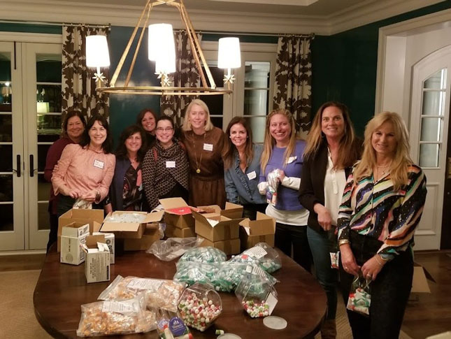 Ten women pose for a photo around a table at the member friendraiser. 