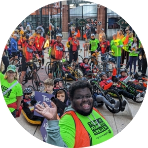 Team Kennedy Krieger poses for a photo during the Baltimore Running Festival. They are standing inside of Oriole Park at Camden Yards, with a gate behind them.