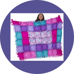 A young girl holds a multi-colored, checkered pattern blanket. 