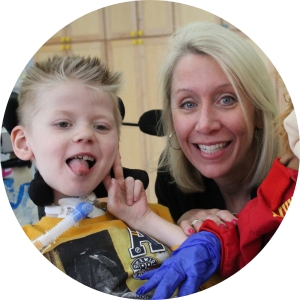 A woman and a young boy in a wheelchair smile in a photo.