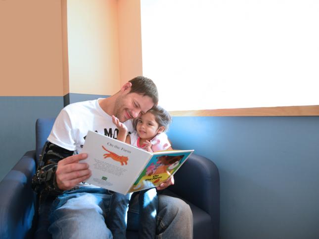 Patient Sanayah Pineiro sits with her dad as he reads her a book