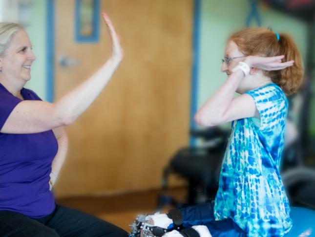 Kennedy Krieger patient Ellie high-fives a therapist