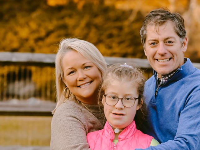 A Kennedy Krieger patient and her parents smile in their backyard.