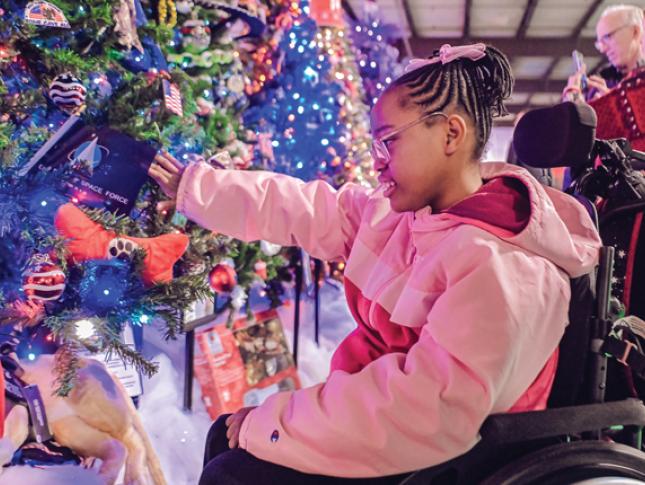 A little girl smiles while looking at a lighted grove of trees at Festival of Trees.