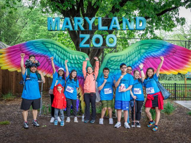 ROAR for Kids participants stand in front of a colorful winged sculpture at the Maryland Zoo.