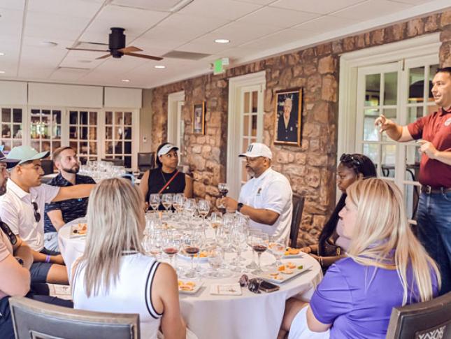 A group of people sit at a round banquet table during Tees and Tastings