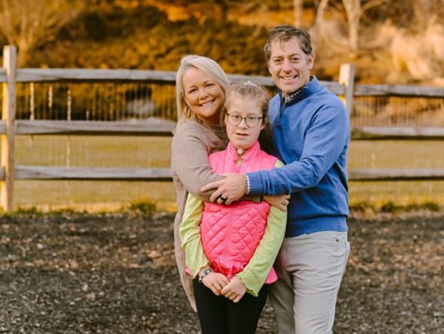 A Kennedy Krieger patient and her parents smile while standing in their backyard.