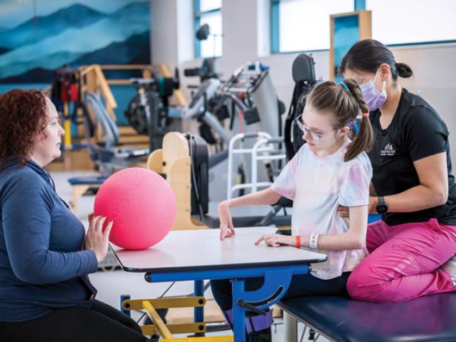 Two physical therapists and a little girl during a session in one of Kennedy Krieger's therapy gyms.