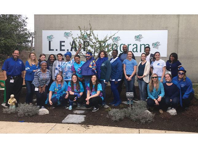 LEAP program staff members pose for a photo in a garden outside the school building.