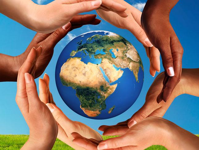 Multiracial hands making a circle together around the Earth.
