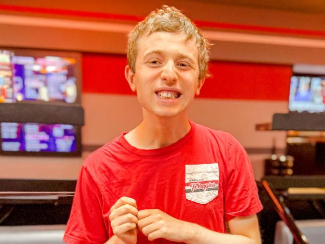 A Neurodiversity at Work intern smiles at an event at a bowling alley.