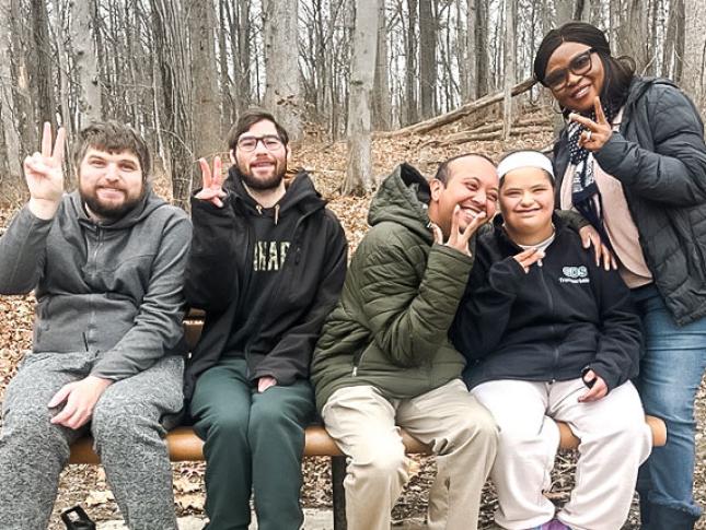 Neurodiversity at Work participants sit on an outdoor bench and smile.