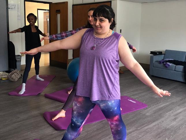 A young woman stands on a yoga mat during yoga.