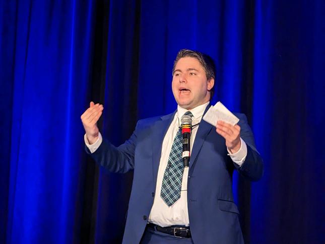 A man in a gives a speech while holding index cards at the 2023 Neurodiversity in the Workplace Conference.