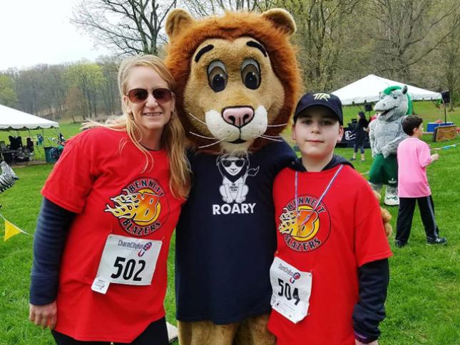 A Bennett Blazer and his mother pose with a mascot lion at ROAR. 