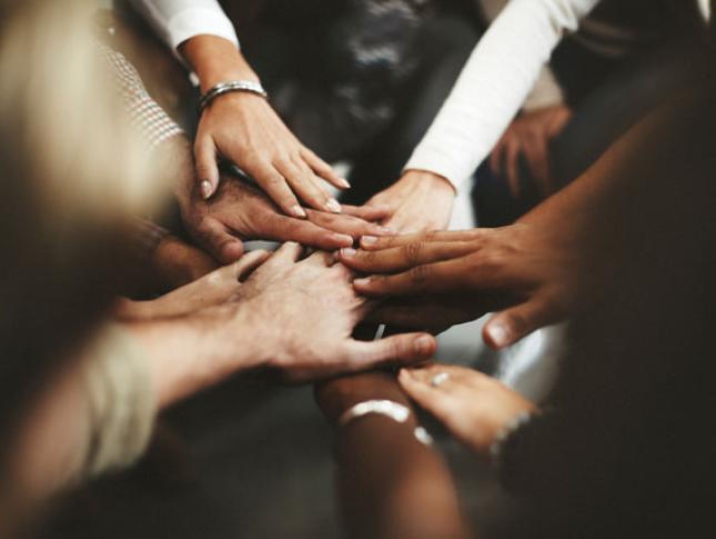 Joined hands in a circle, symbolizing team work.