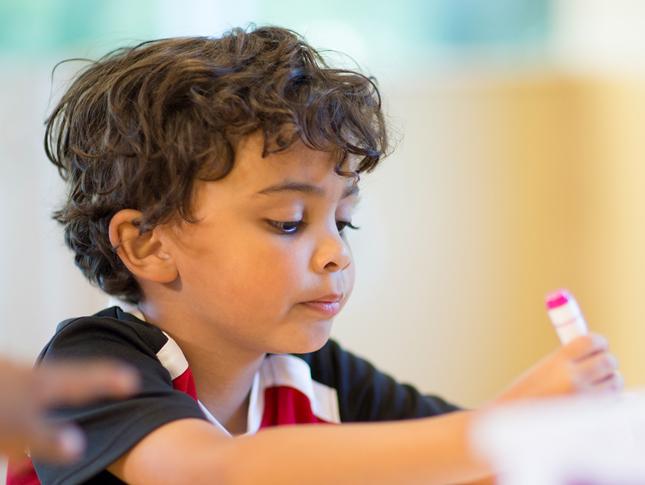 A boy writes with a magic marker.