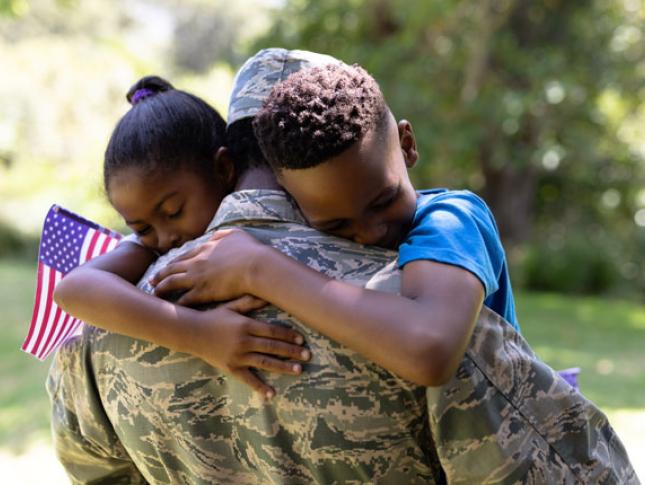 A soldier hugging his son and daughter.