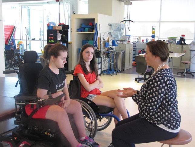 Patients in wheelchairs speaking with a doctor.