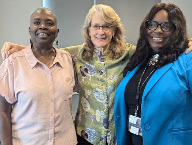 Three women wearing professional attire stand and for a group photo.