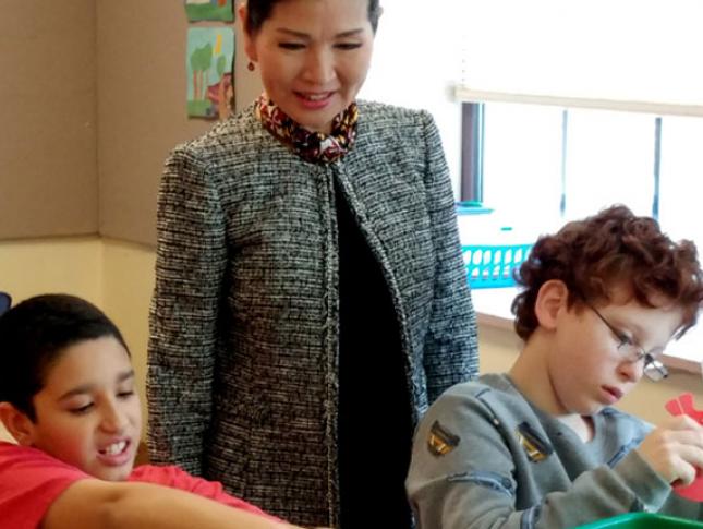 Yumi Hogan, first lady of Maryland, stands behind two students as they work at their desks.