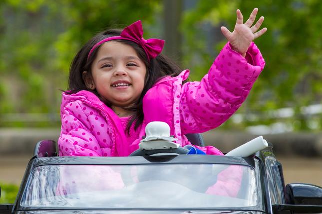 3-year old patient Sanayah waves from a modified car