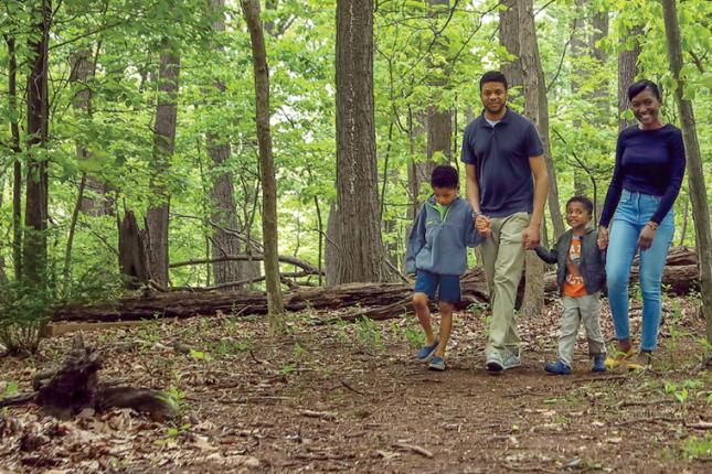 Pictured is Kennedy Krieger patient Dale walking through the woods as he holds hands with his mom, Gina, his dad, Gill, and his little brother, Myles.