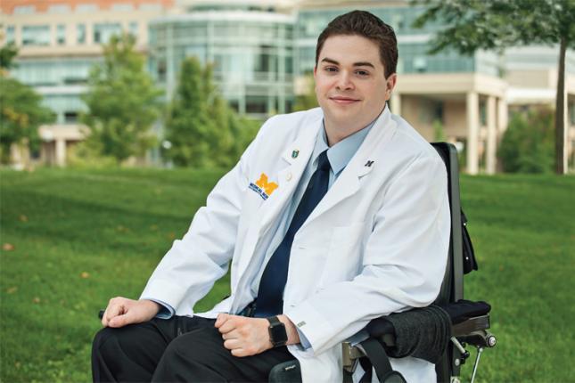 Chris Connolly poses wearing his University of Michigan Medical School white coat