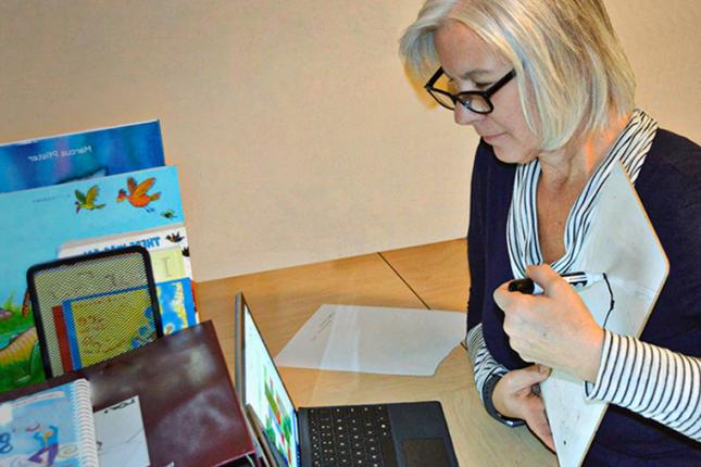 A therapist looks at a laptop screen as she carries out a telehealth appointment