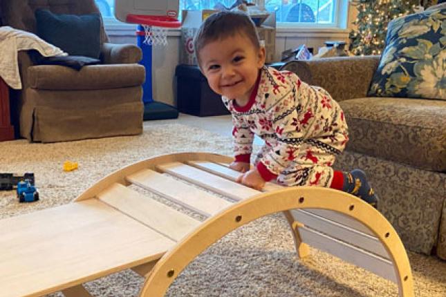 Shepard, a toddler, climbs on a toy.