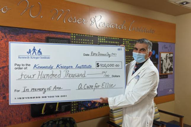 Dr. Ali Fatemi holds large check during the Cure for Ellie Check presentation 2021.