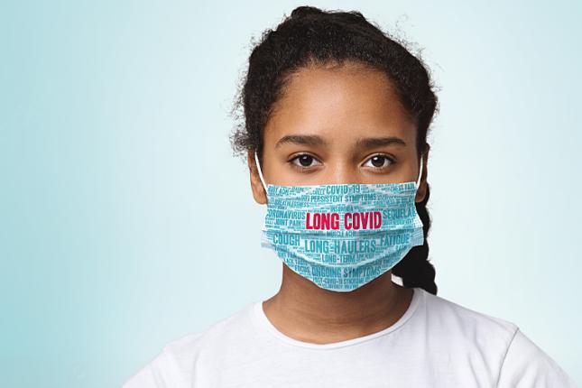 A young girl wears a facemask that says LONG COVID.