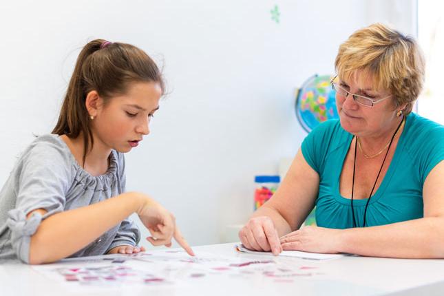 A young girl works on a project with her therapist.