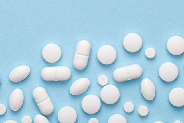 White medical pills lay scattered against a blue background.