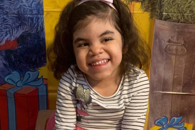 Violet smiles while sitting in a small chair.