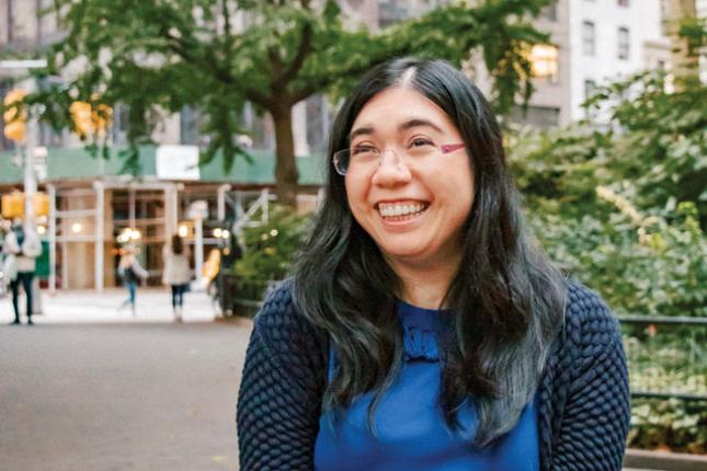 Valerie, smiling, sits in a wheelchair in an urban setting