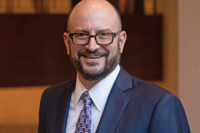 Portrait photo of a man wearing glasses and a suit and tie