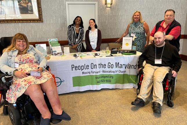 People on the Go Maryland team surrounds the POG exhibitor table at The Arc Maryland State Convention.